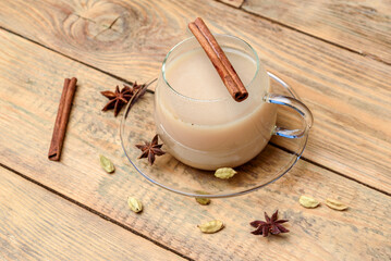 Masala tea in a glass mug with a cinnamon stick.