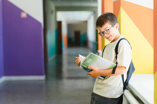 Smiling pupil reading a book in school corridor - Powered by Adobe