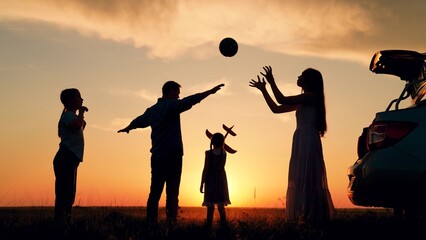 Family, parents children travel car. Dad mom kids campsite in car. Mother father children play with ball, toy airplane. Parents children, daughters having fun time at sunset. Group people nature, sky