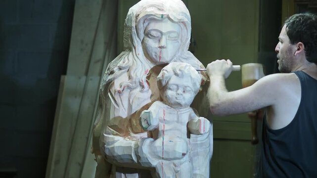 Wood sculptor carving a religious statue of Madonna and child