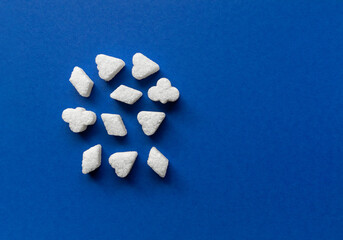White sugar peace cubes in the form of figurines on blue background. Top view closeup.