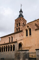 Fototapeta premium Historic architecture shines in Segovia, Spain, with ancient stone structures and a prominent bell tower.