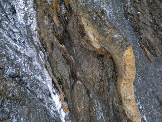Dramatic Winter Cliff Face With Snow Dust On Jagged Stone Walls and Arch
