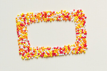 Sweet sugar multicolored sprinkles pile, granules frame on a light pastel background, top view	