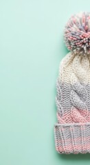 Fototapeta premium Bright colorful knitted winter hat on mint background with snow effect, 4K image