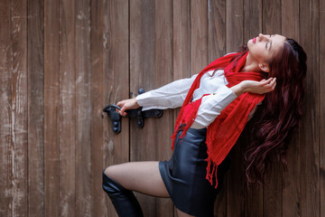 Young woman posing in front of wooden door with red scarf