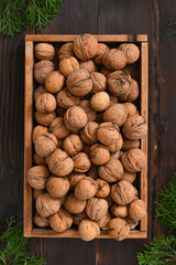 harvest of walnuts in a box on a wooden background