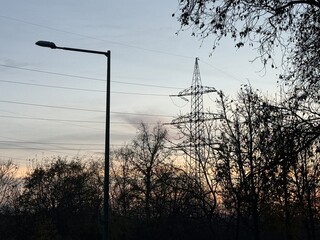 Electricity pylon silhouette at sunset in autumn forest
