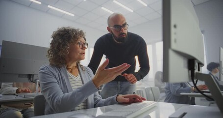 Middle Aged Female Student Works on Computer Project While Teacher Stands Beside, Guiding and Reviewing Progress. Concept Adult Education, Mentoring, Digital Learning, and Professional Development.