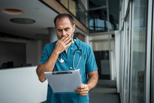 Male doctor feeling worried and stressed examining medical record