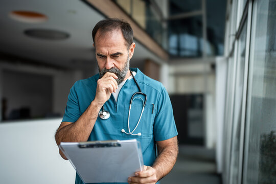 Doctor considering medical diagnosis while reading patient record