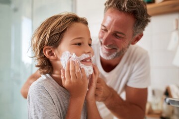 Father and son applying shaving cream in a bright bathroom