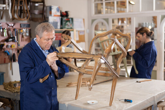 Mature male carpenter working on making vintage chair in workshop