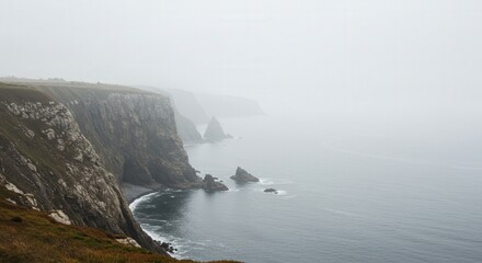 Fog-covered rocky coastal cliffs fading into soft morning haze over calm ocean waters, providing a serene minimal landscape perfect for text projection