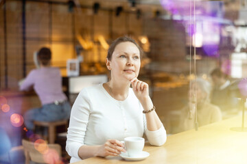 Relaxed woman sitting alone drinking coffee in quiet cafe