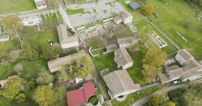Aerial view of the ancient Roman ruins of Saepinum, where weathered stone structures contrast with the vibrant green grass, Sepino, Molise, Italy.