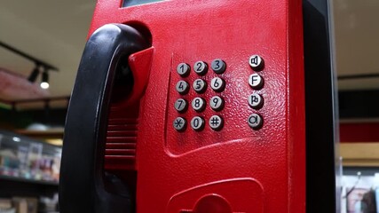 A classic red phone sits atop a countertop, awaiting use