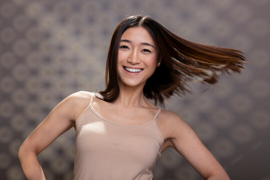 Positive asian person with radiant skin and soft candid smile posing in studio, advertising natural beauty and body positivity. Showing self acceptance with graceful energy and authenticity.