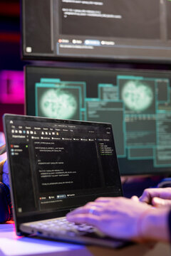 Close up of hacker using malicious malware software on laptop to compromise devices and digital networks, gaining passwords. Man using notebook, stealing, exploiting and illegally selling data online