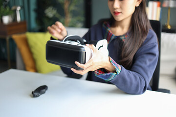 Young asian woman wearing virtual reality glasses in living room at home.