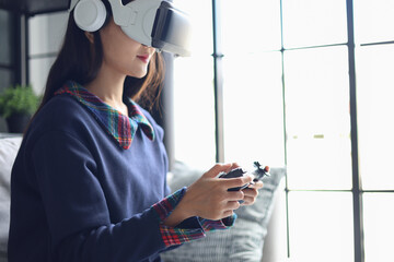 Woman playing video games wearing virtual reality glasses in the living room.