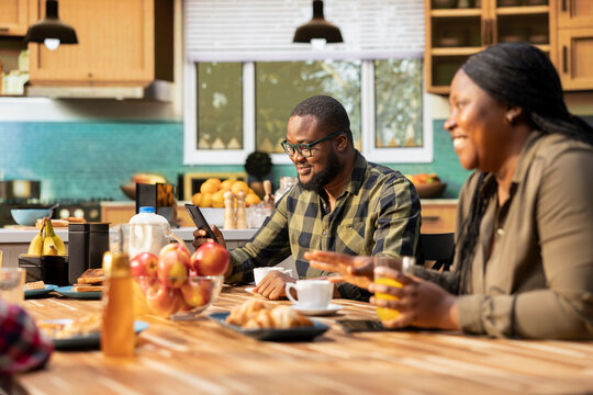 African american working dad on his phone ignoring the family at breakfast table, absorbed disconnected man distracted by his remote work. Inattentive parent distant with his children and wife.