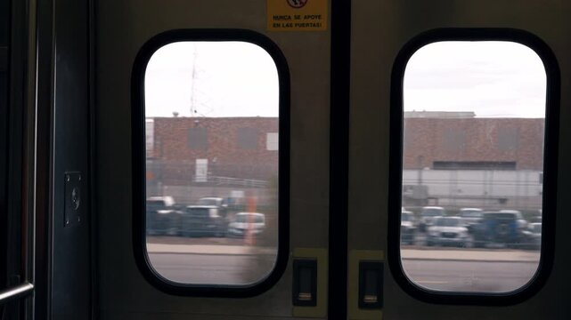 Static shot of light rail train doors framing an industrial Denver landscape as the train moves slowly along the tracks.