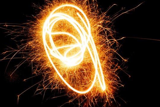 Bright sparkler light trails creating an artistic representation against a dark background, showcasing creativity and festive celebration in a dynamic manner