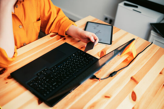 woman holds credit card making online purchases at home., sits at wooden desk with laptop and tablet, focused on transaction