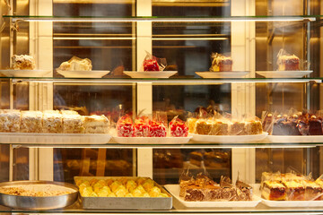 Display case filled with assorted desserts, showcasing colorful pastries, cakes, and sweets, inviting customers to indulge in delightful treats