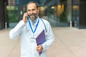 Mature doctor smiling talking on mobile phone outdoors