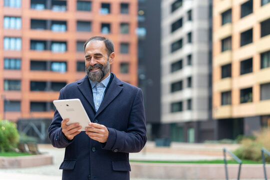 Mature businessman smiling using digital tablet outdoors