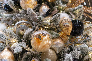 Close-up view of a decorated Christmas tree, made of artificial materials with white snow-like decorations, featuring multi-colored, spherical ornaments, translucent and patterned Ambient lighting s