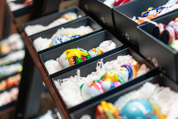 New Years Christmas decorations, colorful glass eggs in black boxes displayed in a showcase, showcasing intricate patterns and vibrant colors