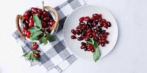 Top view of dogwood berries in rustic bowl and on ribbed ceramic plate with green leaves and fabric