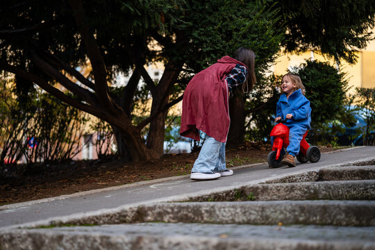Mother and child playing outdoors with tricycle - Powered by Adobe
