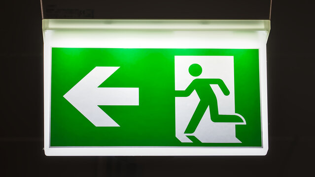 Illuminated emergency exit sign at night, glowing clearly in the darkness as a safety indicator. - Powered by Adobe