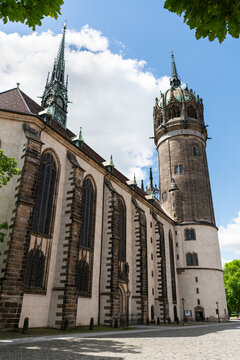Side view of the Castle Church in Wittenberg, framed by leaves. Historic site where Martin Luther posted the 95 Theses.