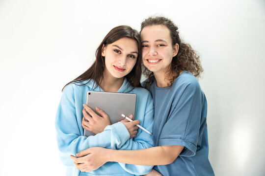 Close friends smiling while posing with tablet. Girls with gadgets - Powered by Adobe