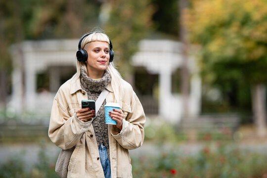 Young woman enjoying music outdoors during autumn