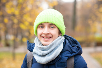 Portrait of a 13-year-old boy in a jacket with a backpack in the autumn park