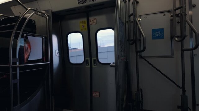 Static shot inside a light rail car showing doors, bike rack, metal bars and window view of the passing landscape outside Denver.