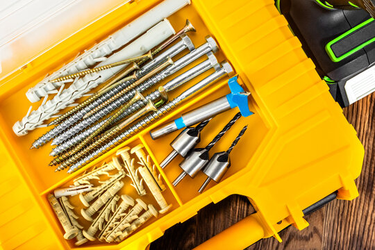 Photo of plastic screws and bits organizer laying on wooden table surface.