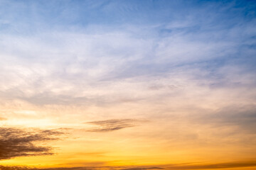 Sunset or sunrise sky with a vibrant gradient of orange, gold, and soft blue. Clear atmosphere with wispy clouds. Peaceful, natural light background. hope, freedom, new day and inspirational Concepts