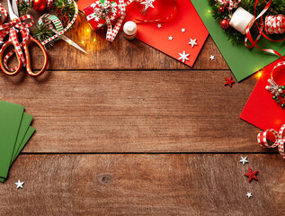 Overhead view of christmas gift wrapping essentials and festive decor on a warm wood surface.