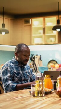 Vertical Video African american man working too hard and woman asking for a break, showing him the timeout sign and closing his laptop. Workaholic boyfriend ignoring his girlfriend during breakfast