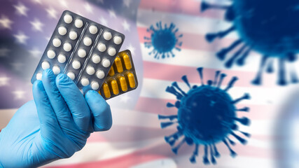 Medicine and healthcare concept with hand holding pills against US flag and virus symbols,...