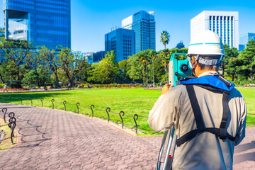 Land surveyor uses total station equipment for topographic measurements, preparing urban development and construction planning in city area.
