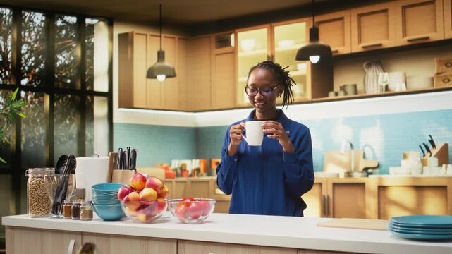 Happy adult in the kitchen smelling the fresh aroma of roasted coffee, serving delicious homemade breakfast. Woman uses prepare slices of toast with croissants and enjoys warm coffee cup. Camera A.