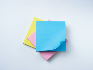 Three colorful sticky note pads—blue, yellow, and pink—stacked and slightly rotated on a white background.